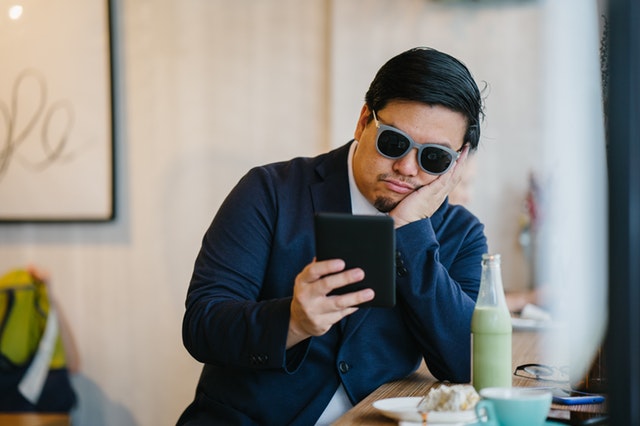 man-wearing-grey-sunglasses-holding-black-tablet-1507931
